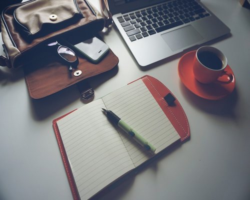 Organized desk with a notebook, pen, and a cup of tea